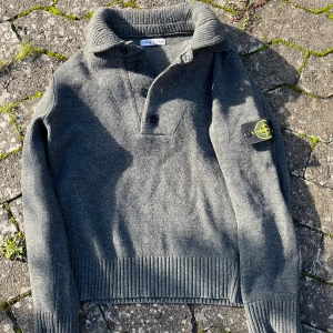 Stickad Tröja Från Stone Island  - En riktigt cool vintage tröja från Stone Island! En gammal modell men i förvånansvärt bra skick med alla knappar och även extraknappar kvar! Strl M. OBS eftersom det är en modell äldre än 2014 finns det ej någon Certilogo qr kod! Hade lite svårt att prissätta denna då det ej finns så många liknande på marknaden så var inte rädda för att lägga ett prisförslag!