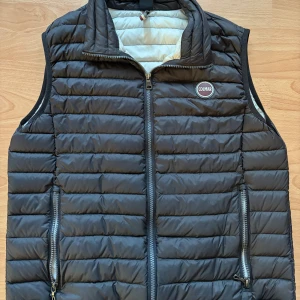 Svart dunväst från Colmar, strl 50/M - Snygg svart dunväst från Colmar Originals med quiltad design och dragkedja framtill. Västen har två praktiska fickor med dragkedja och en ljus insida. Sitter riktigt bra och är i väldigt gott skicka. Priset är inte hugget i sten!. Det är bara att skriva ifall du har några frågor😁