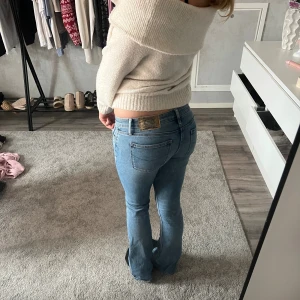 Crocker low bootcut jeans ljusblå - Säljer ett par klassiska crocker  jeans i ljusblå tvätt med bootcut passform. Byxorna har fem fickor, låg midja och snygga slitningar framtill. Perfekt för dig som gillar retrovibbar och vill ha en tidlös jeansstil.