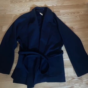 Mörkblå omlottjacka med bälte - Säljer denna fina jackan, vet inte märket på den då jag köpte den på plick! I väldigt fint skick!