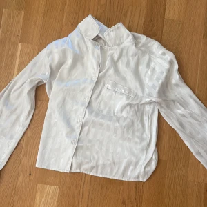Vita randiga satinbyxor och satin tröja från gina Tricot - Snygga vita byxor och satin tröja från Gina Tricot i satin med subtila ränder. De har en relaxed passform, elastisk midja och ett mjukt, glansigt material som känns lyxigt. Perfekta för dig som gillar en chill och stilren vibe.