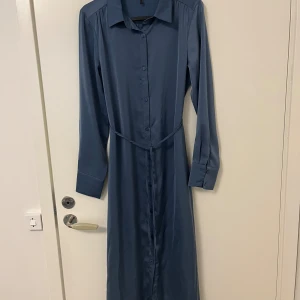 Blå långklänning - Blå långklänning i satinmaterial. Aldrig använd.