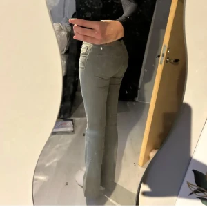 Olivgröna bootcut byxor - Snygga grågröna byxor med bootcut-modell och normal passform. Byxorna är aldrig använda men jag har sprättat upp nederkanten för att få dem löngre 