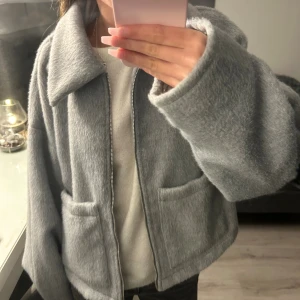 Grå teddyjacka  - Köpt för 599, aldrig använd. Supermjuk och fluffig grå teddyjacka från Vila med stora fickor framtill och dragkedja. Jackan har en oversized passform och bred krage, perfekt för att hålla sig varm och snygg under kyliga dagar.