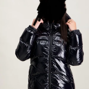 Svart glansig pufferjacka från Colmar - Säljer en svart, glansig pufferjacka från Colmar med huva och dragkedja framtill. Jackan har en quiltad look och är perfekt för kalla dagar. Klassisk passform och diskret logga på ärmen. Riktigt snygg och trendig vinterjacka!