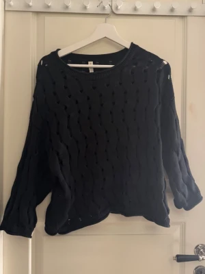 Svart stickad tröja från kay/day - Svart, trekvartsärmad stickad tröja med hål från ett märke som heter kay/day