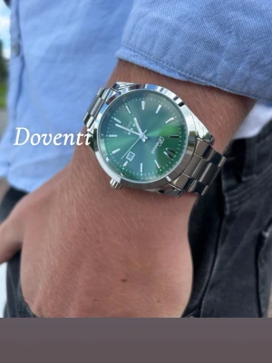 Silverfärgad grön klocka x Doventi  - 🌟 Doventi - Helt ny och oanvänd klocka i toppskick! 🌟 🎁 Levereras komplett med originalbox. ✨ Perfekt skick, garanterat utan defekter. ⚙️ Enkel justering för optimal passform. 🚀 Snabb leverans samma dag – direkt till dig!