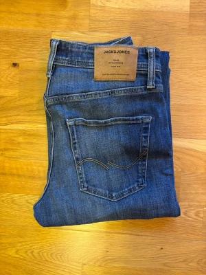 Jack & Jones Tapered/Mike w28/l30 - Snygga blå jeans från Jack & Jones med klassisk femficksdesign och bruna detaljer på bakfickan. Modellen är tapered vilket ger en smalare passform nedtill. Jeansen har gul kontrastsöm och är tillverkade i slitstarkt denimtyg. Perfekt för dig som gillar stilrena och bekväma jeans. OBS INKÖPTA IÅR, KNAPPT ANVÄNDA! MODELL GE 311 NOOS