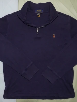 Mörkblå half zip tröja Polo Ralph Lauren - Säljer en mörkblå långärmad tröja från Polo Ralph Lauren med klassisk krage och half zip-dragkedja. Tröjan har broderad logga på bröstet och är gjord i mjuk bomull. Perfekt för chill dagar och snygg till jeans. Tröjans längd = 50 cm Tröjans bredd = 37 cm