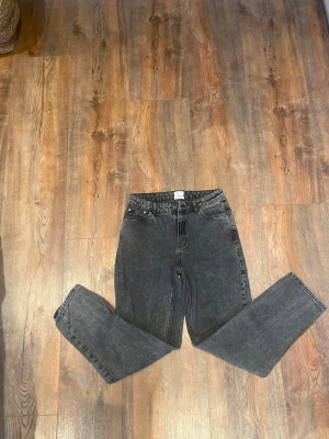 Svarta jeans från Grunt - Säljer ett par svarta jeans från Grunt med fem fickor och klassisk knappstängning. Jeansen har en rak passform och är tillverkade i ekologisk bomull. Snygg tvättad look och stilrena detaljer, perfekta för dig som gillar enkel och clean stil.