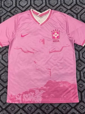 Rosa Brasil Nike fotbollströja - Säljer en rosa Brasil fotbollströja från Nike med CBF-logga och stjärnor på bröstet. Tröjan har v-ringad krage med vita och rosa detaljer samt ett subtilt motiv på framsidan. Perfekt för dig som vill sticka ut på planen eller visa support. ALLA STORLEKAR FINNS!