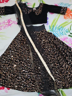 Svart långklänning med paljetter - Säljer en svart långklänning med glittriga paljetter i guld över hela kjolen och på kragen. Klänningen har långärmad topp i sammet och en matchande svart sjal med guldfärgad kant. Perfekt för dig som vill sticka ut med en glamorös look. För barn 4-5 år..