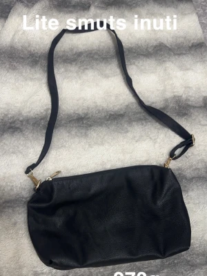 Svart axelväska  - Snygg svart axelväska med justerbar rem och guldfärgade detaljer. Väskan har en enkel, stilren design som passar till många olika outfits. Perfekt storlek för att få plats med det viktigaste och enkel att bära över axeln.🌸 Lite smuts på insidan ( ej tvättad men utborstad)