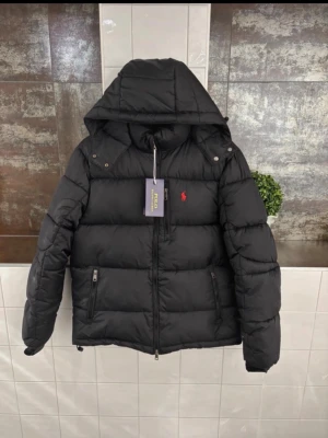Svart pufferjacka från Polo Ralph Lauren - Jätte snygg matt svart Ralph Lauren jacka perfekt för vintern och kommande snön och kylan! Etiketten finns kvar men är ej på som på bilderna! Påsen finns också kvar och både etiketten och Ralph Lauren påsen följer med! Har använts fåtal gånger. Säljs då jag fick en ny jacka i present! Storleken är S passar någon som är 170-183.