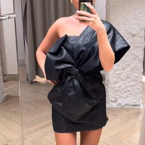 Svart glittrig oneshoulder klänning rosett - Svart glittrig mini-klänning från H&M med en stor rosett framtill, oneshoulder. Även silikonremsa inuti (sista bilden) så den sitter uppe extra bra! Helt oanvänd, perfekt till jul, nyår och fest🖤✨🪩finns ej att köpa längre 