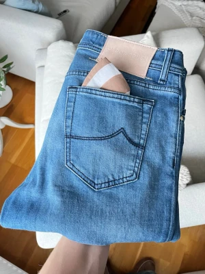 Jacob Cohën jeans  - Snygga blå jeans från Jacob Cohen, modell Bard. Klassisk femficksdesign med ljusblå tvätt och raka ben. Jeansen har knappar i metall och detaljerad insida. Tillverkade i mjukt denim-material för en skön känsla. Perfekt för dig som gillar stilrena och exklusiva jeans.