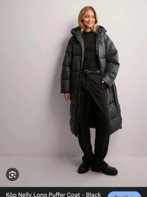 Svart lång pufferjacka från Nelly - Säljer denna super fina jackan från Nelly, köpt förra året. Använd ett oar gånger, har lite sminkfläckar vid luvan 