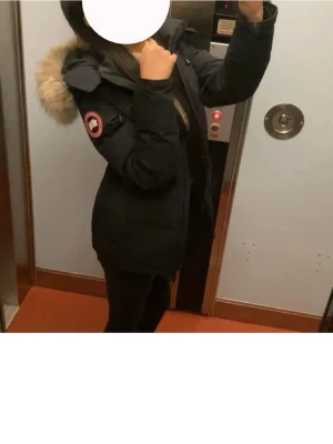 Svart Canada Goose dunjacka med päls - Canada goose jacka i modellen Chelsea parka. Storlek XXS. Jackan är marinblå med ser ut som svart. Det finns ett jättelitet hål på båda ärmen, men annars finns det inga andra defekter. Pris går att diskutera. Skriv för fler bilder! 