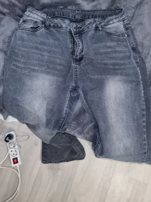 Mörkgrå jeans med straight fit - Snygga mörkgrå jeans med tvättad look och klassisk femficksdesign. Modellen har utsvängd passform och normal midja, med dragkedja och knapp framtill. Materialet är robust denim som passar perfekt till en chill stil. Baksidan har två fickor med tydliga sömmar.