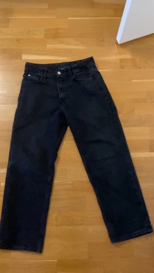 Svarta loose fit jeans från H&M - Svarta jeans från H&M med loose fit och rak passform. Justerbar midja för extra komfort. Klassisk femficksdesign och raka ben. Perfekta för dig som gillar en avslappnad stil och vill ha jeans som sitter skönt hela dagen.