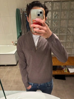 Brun half zip tröja från Stenströms - Säljer en stilren brun långärmad tröja från Stenströms med half zip och ribbade muddar. Tröjan är i mjuk bomull och passar perfekt till jeans eller chinos. Enkel och clean look med hög krage och diskret dragkedja.