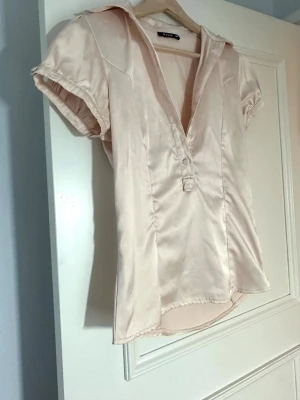Ljusrosa blus i satin  - En så fin figursydd ljusrosa blus i satin från Vila🤍saknar en knapp men är för övrigt i mycket gott skick. Har en dragkedja i sidan.