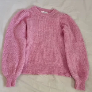 Jättefin gullig rosa stickad tröja från Selected Femme - Supermysig rosa stickad tröja från Selected Femme i storlek XS. Tröjan har en rund halsringning, ballongärmar och ribbade muddar. Passar lika bra till jeans som till kjol. Mycket bra skick, aldrig använd – visst noppigt och luddigt, men i övrigt hel och fin. Känns något sträv mot huden så rekommenderas med ett linne/t-shirt under för bästa komfort. Nypris runt 700 kr. Säljer den då jag inte får någon användning för den. 