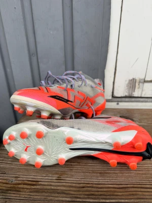 Puma fotbollsskor ultra future  - Säljer ett par snygga Puma fotbollsskor med låg profil och platt sula. Skorna är vita med starka röda och svarta detaljer, har snörning och mönstrad ovandel i syntetmaterial. Sulan har röda dobbar för bra grepp på planen. Perfekt för dig som vill sticka ut på matchen! Skorna är använda max 3 gånger så inprencip helt nya! Rek pris 2700kr! Pris kan diskuteras! 