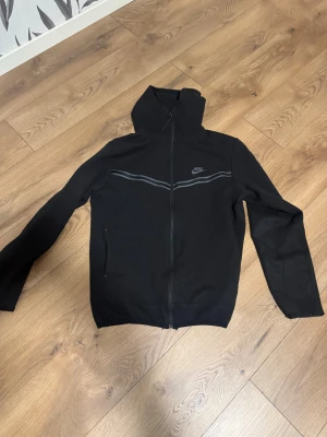 Nike tech - Svart vindjacka från Nike med hel dragkedja och huva. Den är som ny, har använt den ca 2-3 gånger