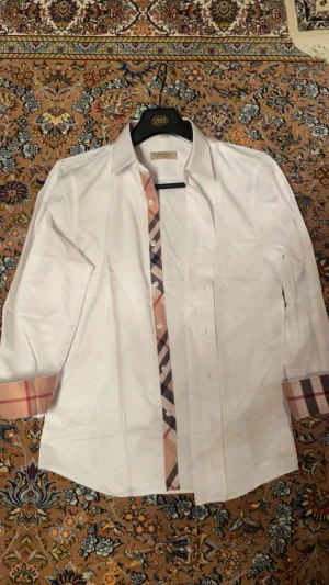 Vit Burberry skjorta med rutiga detaljer - Säljer en tvärfet Burberry skjorta. Den står M men sitter som S. om du har några frågor är det bara att ställa dom!