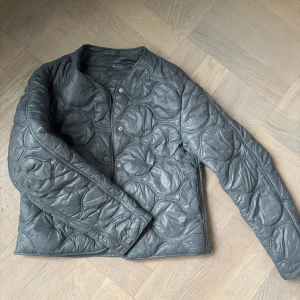 Grå quiltad pufferjacka XS - Säljer en grå quiltad pufferjacka från Zara i storlek XS. Jackan har rund halsringning, tryckknappar framtill och ett coolt cirkelquiltat mönster. Perfekt för dig som vill ha en lätt och trendig jacka till vardags.
