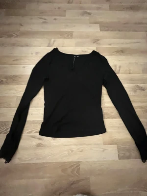 Svart långärmad topp med spetsdetaljer - Svart långärmad topp från H&M med snygg v-ringning och spetsdetaljer både vid halsen och ärmsluten. Modellen är slim och har en mjuk känsla, perfekt för dig som gillar stilrena plagg med en liten twist. Materialet är bomull och polyester.