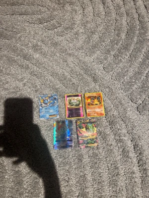 Pokémonkort - Blandad samling - Cool samling med 5 Pokémonkort, inklusive populära karaktärer som Charizard och Vaporeon. Perfekt för dig som vill utöka din samling eller börja spela Pokémon TCG. 2 kort är lite skadade där bak bara. Resten är i bra skick