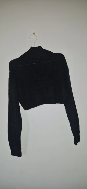 Croppad polotröja - Svart croppad polotröja från H&M i ribbstickat material. Tröjan har lång ärm och en hög krage som ger en snygg och trendig look. Perfekt att styla med höga jeans eller kjol för en cool vibe.