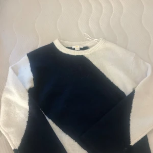 Randig stickad tröja från Gina Tricot - Snygg stickad tröja från Gina Tricot i storlek 146/152. Tröjan har ett coolt diagonalt randigt mönster i svart och vitt, rund halsringning och långa ärmar. Perfekt för dig som gillar en stilren men ändå trendig look.
