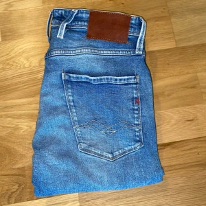 Replay Anbass  - Tjena! Säljer dessa snygga Replay Anbass jeans med snygga slitningar och en klassisk femficksdesign. Materialet är mjukt och lite stretchigt. De har en rak passform med dragkedja och knapp framtill. Använda men i väldigt bra skick. 📏Storlek: W30/L32 💰 Nypris: 1800 kr ⚡ Mitt pris: 699 kr. Hör gärna av dig om du har några frågor eller vill se fler bilder!