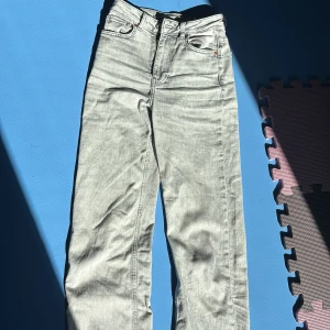 Gråa high waist wide jeans från Gina Tricot - Snygga grå jeans från Gina Tricot med hög midja och breda ben. Klassisk femficksmodell med dragkedja och knapp framtill. Jeansen har en ljusgrå tvätt och är tillverkade i mjukt denimtyg. Perfekta för en trendig och avslappnad look. Använda 1 gågn men märkte att dom var förstora för min bekvämlighet. Annars skulle jag säga att det är xs som står. 