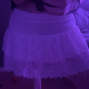 Vit spetskjol med volang - Supersöt vit kortkjol i spets med volangkant. Kjolen har bred midjeresår och har shorts insytt. Passar till många olika looks och är lätt att matcha. 