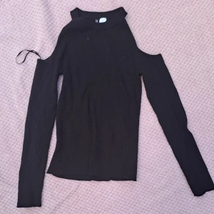 Svart ribbad topp med cut out-axlar - XS - Svart ribbad topp med cold shoulders. Köpte den näe jag var liten för jag trodde det var coolt och vuxet. Den är fortfarande väldigt mjuk och skön och den förtjänar användning men den är lite för stor för mig och jag tycker inte så mycket om svart