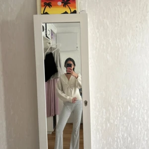 Vit stickad tröja med twist framtill - Superfin vit stickad tröja med twistad detalj framtill och v-ringning. Tröjan har långa ärmar och en lite loose passform, perfekt för lager-på-lager. Enkel att matcha med både jeans och kjol.