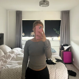 Grå långärmad topp med öppen rygg - Säljer en stilren grå långärmad topp med tight passform och snyggt öppen rygg. Toppen är enkel men ändå trendig, perfekt att matcha med både jeans och kjol. Materialet känns mjukt och stretchigt, vilket gör den riktigt bekväm att bära.