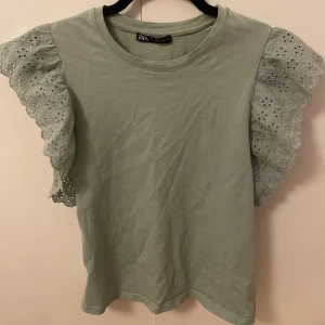Grön blus med broderade volangärmar Zara - Supersöt ljusgrön blus från Zara med broderade volangärmar i blommigt mönster. Toppen har rund halsringning och är tillverkad i mjuk bomull. Perfekt för dig som vill ha en feminin och trendig look med extra detaljer på ärmarna. Tyvärr har varan lite rynkor men det går snabbt att fixa med strykjärn ☺️