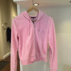 Rosa hoodie från Juicy Couture - Använd Max 1 gång som ny. Orginal pris 1200-1500. Supermjuk rosa hoodie från Juicy Couture i velour med dragkedja och huva. Klassisk JC-logga broderad på bröstet och snygg J-detalj på dragkedjan. Perfekt för en chill och trendig look. 🥰🥰