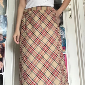 Retro Rutig lång kjol  - Retro kjol ca 80/90-tal. I fint skick dock finns lite noppror och ett litet slitage vid dragkedja (se bild). Passar någon med Small. Jag kan mötas upp i Uddevalla centrum, annars fraktar jag gärna. Köparen står för frakten. (Står ej för postens slarv) katt finns i hemmet. 