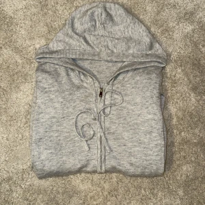 Ljusgrå Kashmir zip från Don - Säljer denna riktigt feta ljusgrå 100% Kashmir zip, storlek S från Don med dragkedja framtill och snörning i huvan. Tröjan är i mjuk bomullsmix, har långa ärmar och två fickor framtill. Perfekt för chill dagar eller när du vill ha en enkel och clean look. Ny pris ca 1000kr, mitt pris 499. Vid funderingar är det bara att höra av sig!