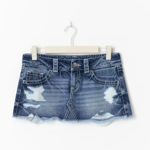 Blå jeanskjol med slitningar - Superkort jeanskjol i blå denim med coola slitningar och rå kant nertill. Klassisk femficksmodell med bälteshällor och knappstängning framtill. Perfekt för dig som vill ha en edgy och trendig look.