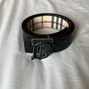 Vändbart burberry bälte - Fett vändbart bälte från Burberry med svart-silvrigt spänne i storlek 95/110cm, hålgörare ingår. Nytt skick och fraktas inom 24h✅