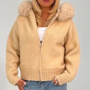 Beige stickad teddyjacka med päls - Supermysig beige teddyjacka med fluffig päls på huvan och grov ribbad kant vid ärmslut och nederkant. Jackan är stickad och har dragkedja framtill, perfekt för dig som gillar chill och stilren vibe. Passformen är loose och jackan har långa ärmar.