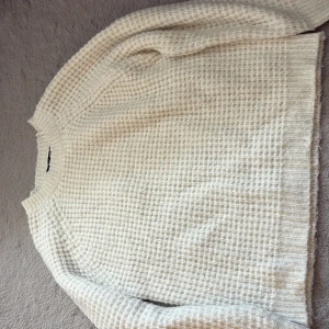 Vit stickad tröja från lager 157 - Säljer en beige stickad tröja från lager 157 i storlek XS. Tröjan har ett grovt, rutigt stickmönster och ribbade muddar vid hals, ärmslut och nederkant. Perfekt för dig som gillar en enkel och chill stil med lite struktur.