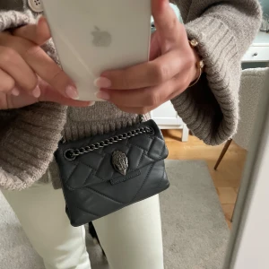 Grå Kurt Geiger väska  - Jättefin väska som har några små defekter på undersidan som ni ser på sista bilden. Väska är i bra skick oavsett skvavaderna på undersidan och att den har lite läppstifts fläckar inuti (be mig skicka bild om ni vill se). Pris går att diskuteras!! 